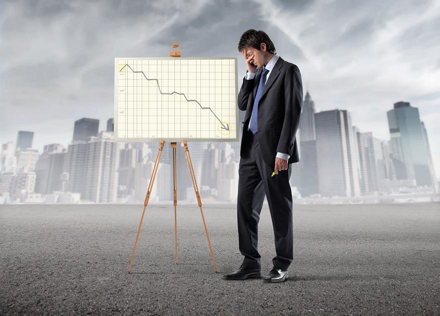 Worried businessman standing beside a graphic with negative trend and cityscape in the background